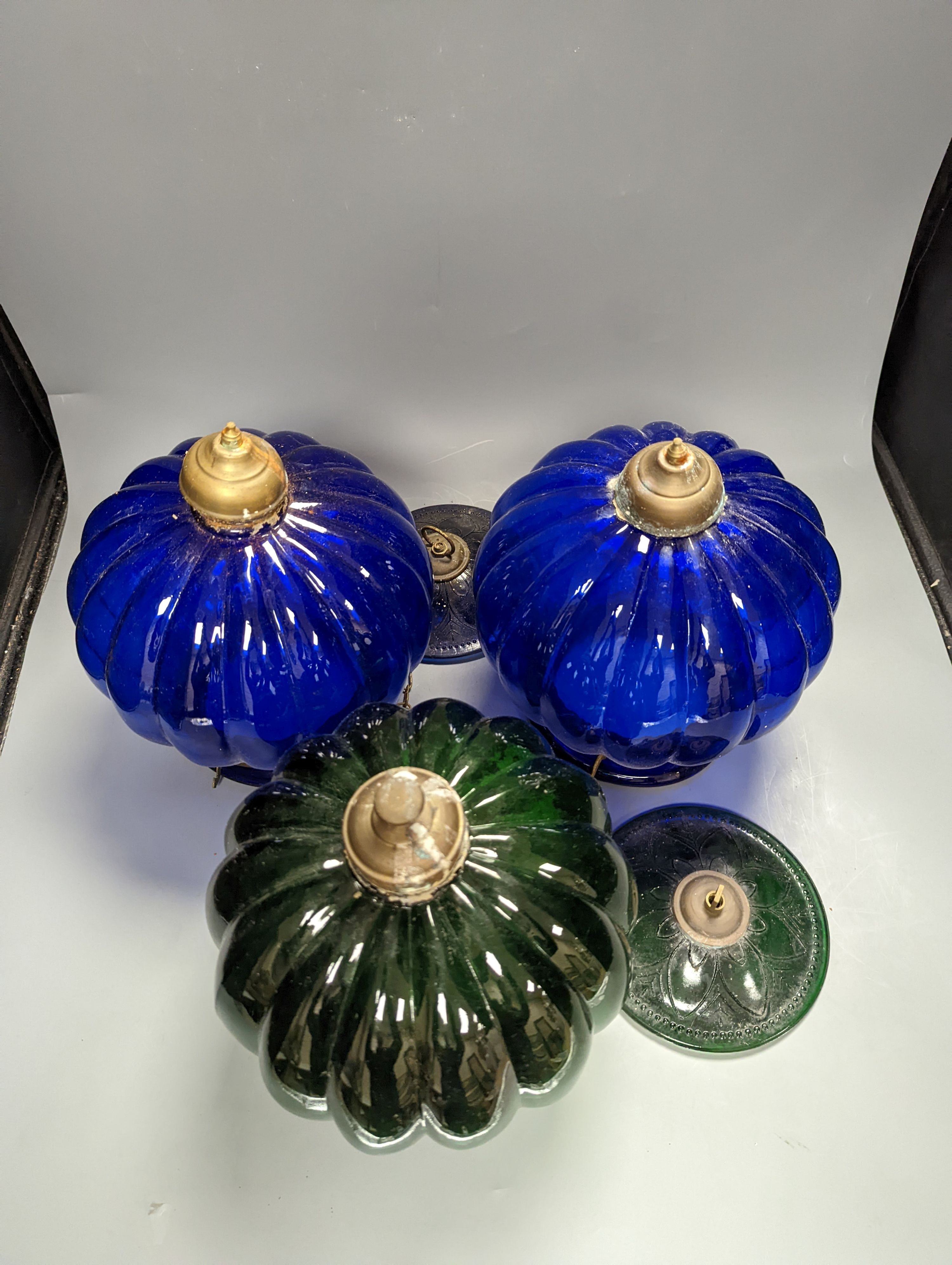 Three coloured glass pendant fluted globe shaped lamps - two blue, one green, 30 cms high.
